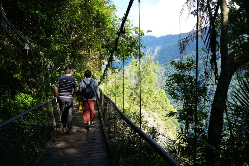 一行人走過架在山壁上的木棧道