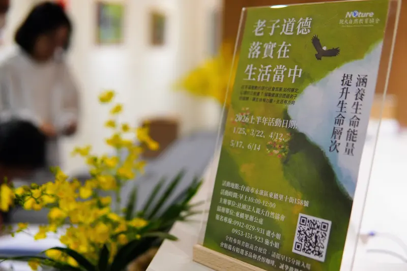 桌上立著「老子道德 落實在生活當中」的立牌,旁邊是黃色花藝