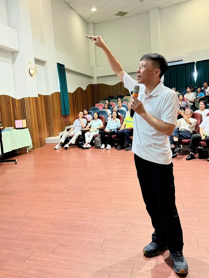 老師舉起手示意,身後是整排座位