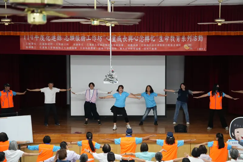 舞台上一排人張開雙臂帶動作