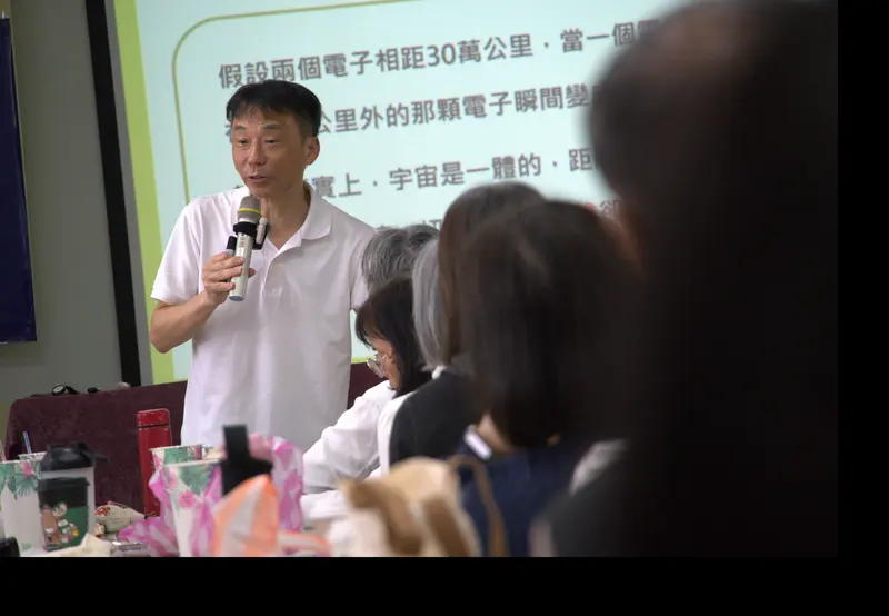 講者拿著麥克風講解投影幕上的內容